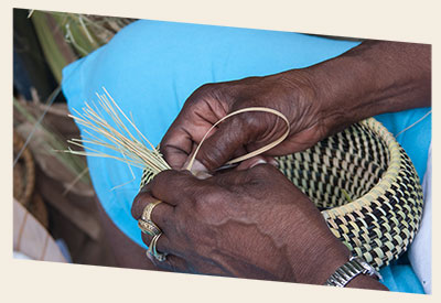 Image close up of the hands of a Gullah woman weaving a basket by hand