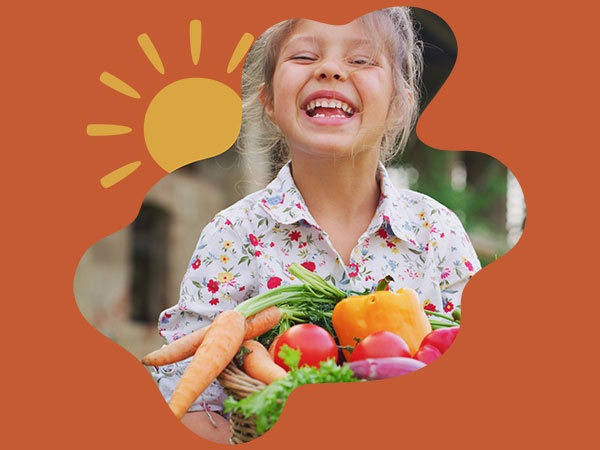 Image of a young girl smiling while carrying a basket of fresh produce